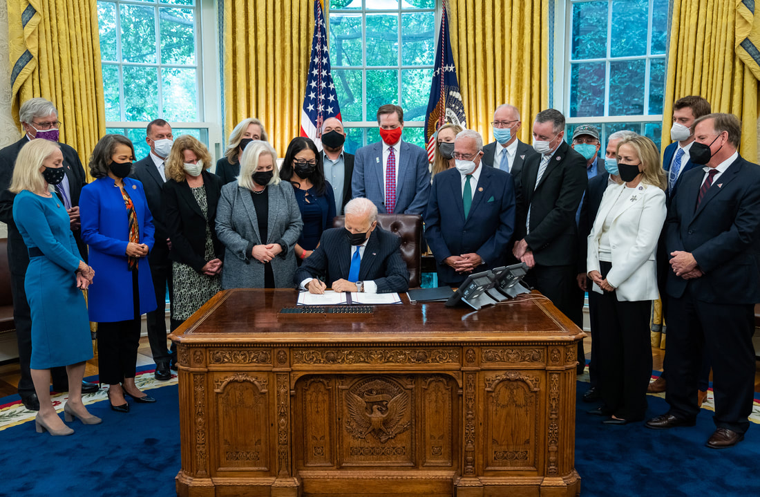 President Biden signing legislation surrounded by group of people